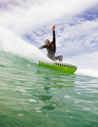 Person surfing on a green and whiteboard with a blue sky 